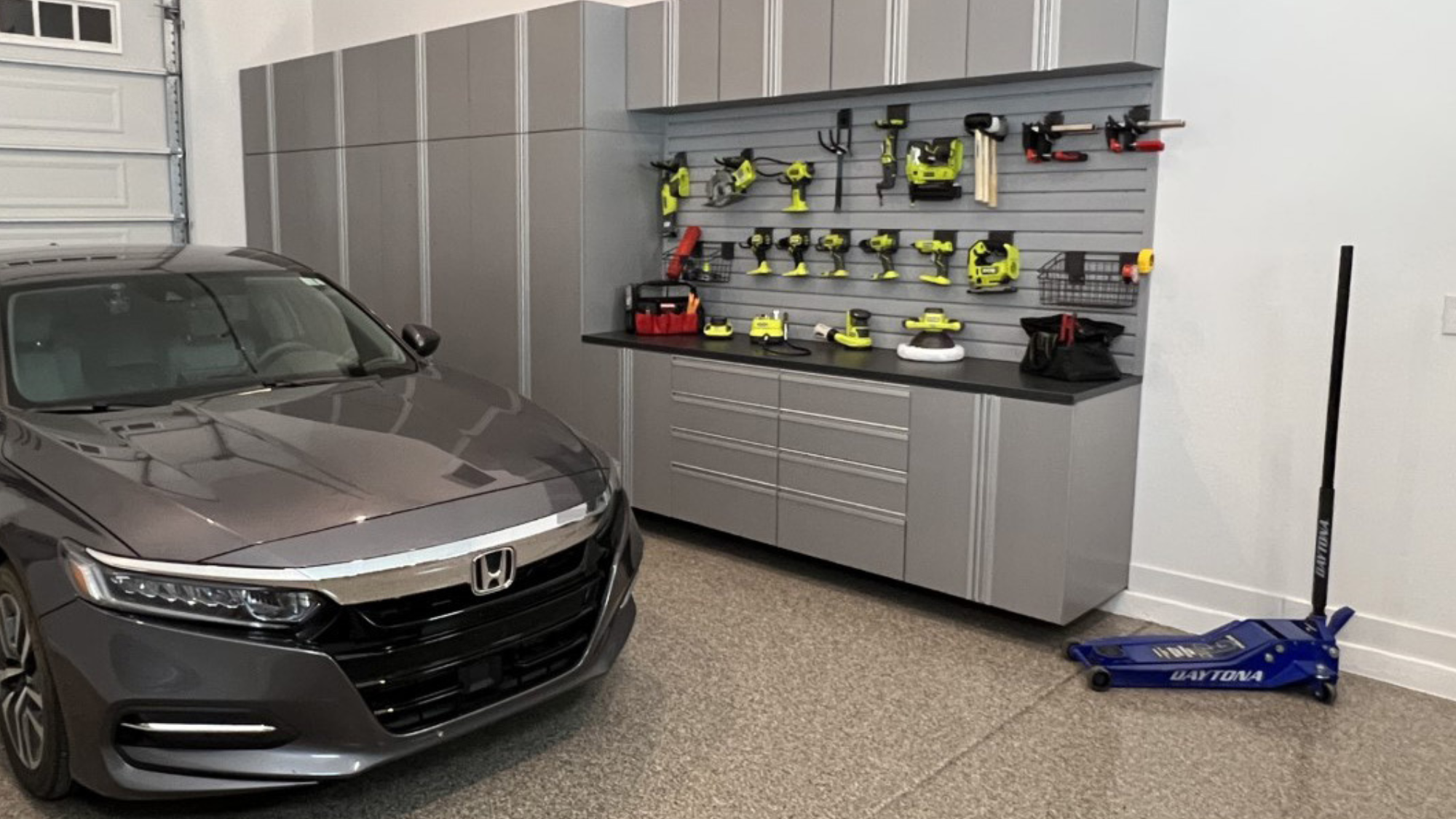 Custom garage storage system with cabinets and slat wall in a Phoenix, AZ home